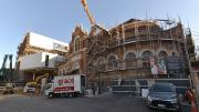 Heritage building surrounded by scaffolding and to the left a new white box building.